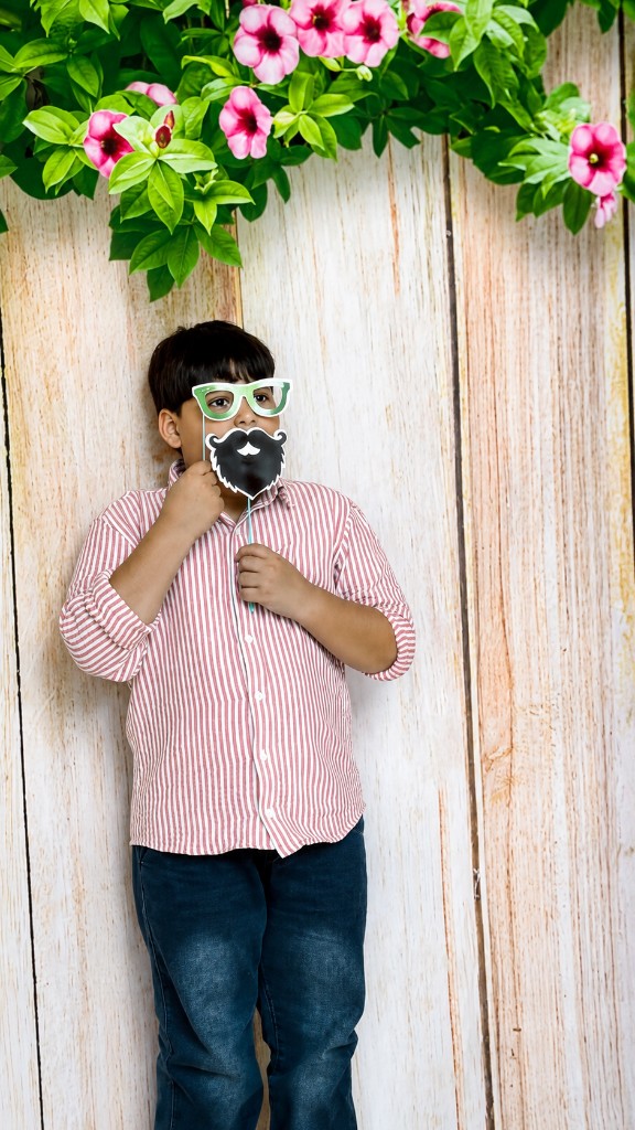 Boy posing with fun photobooth props including glasses and a beard